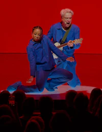 a man and a woman on stage with a guitar
