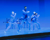 a group of dancers on a stage with blue lights